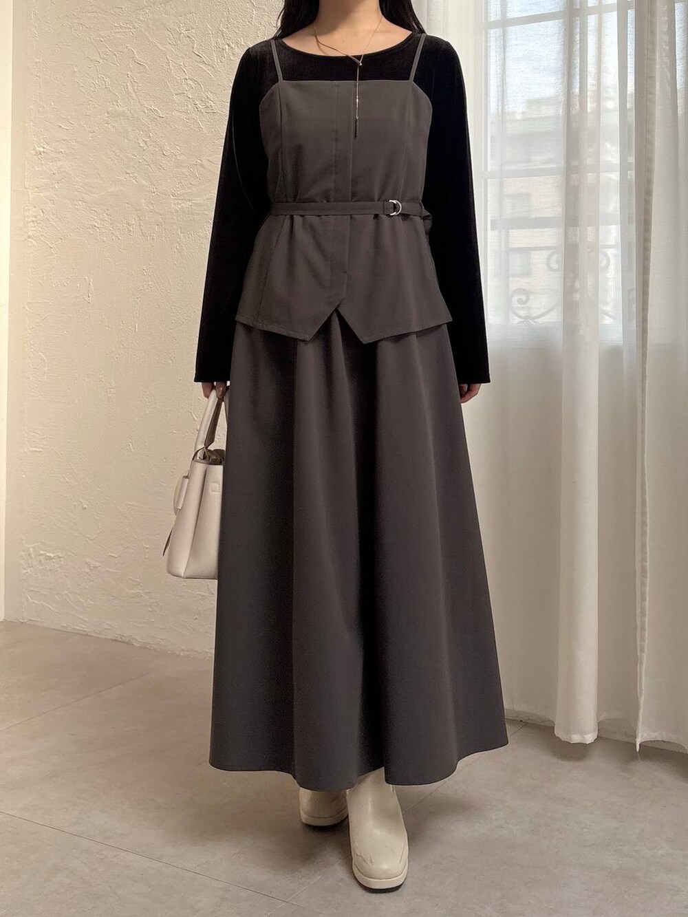 グレー系のワンピース、ホワイト系のブーツ、ブラック系のTシャツ/カットソーを着用したレディースの冬コーディネートの4枚目の写真