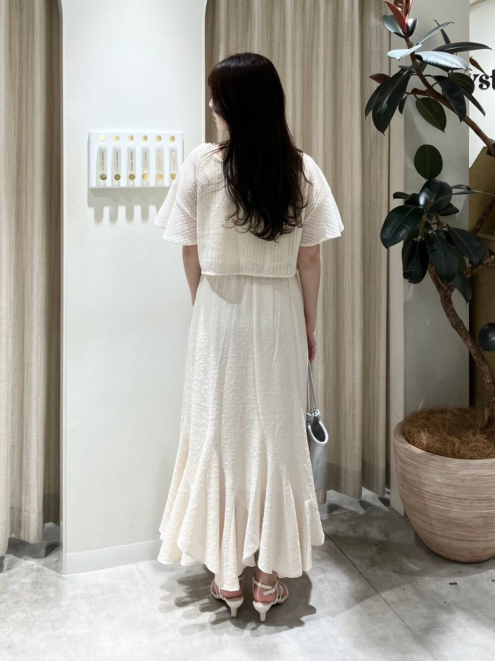 シルバー系のハンドバッグ、ホワイト系のサンダル、ホワイト系のスカートを着用したレディースの春コーディネートの2枚目の写真