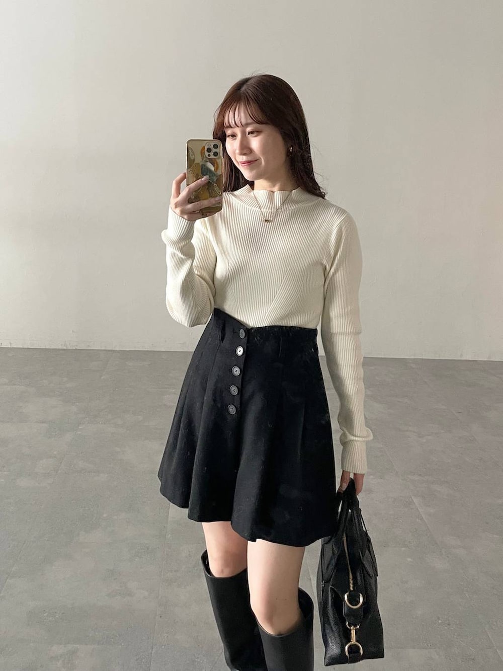 ブラック系のボストンバッグ、ホワイト系のニット/セーター、ブルー系のチェスターコートを着用したレディースの秋コーディネートの3枚目の写真