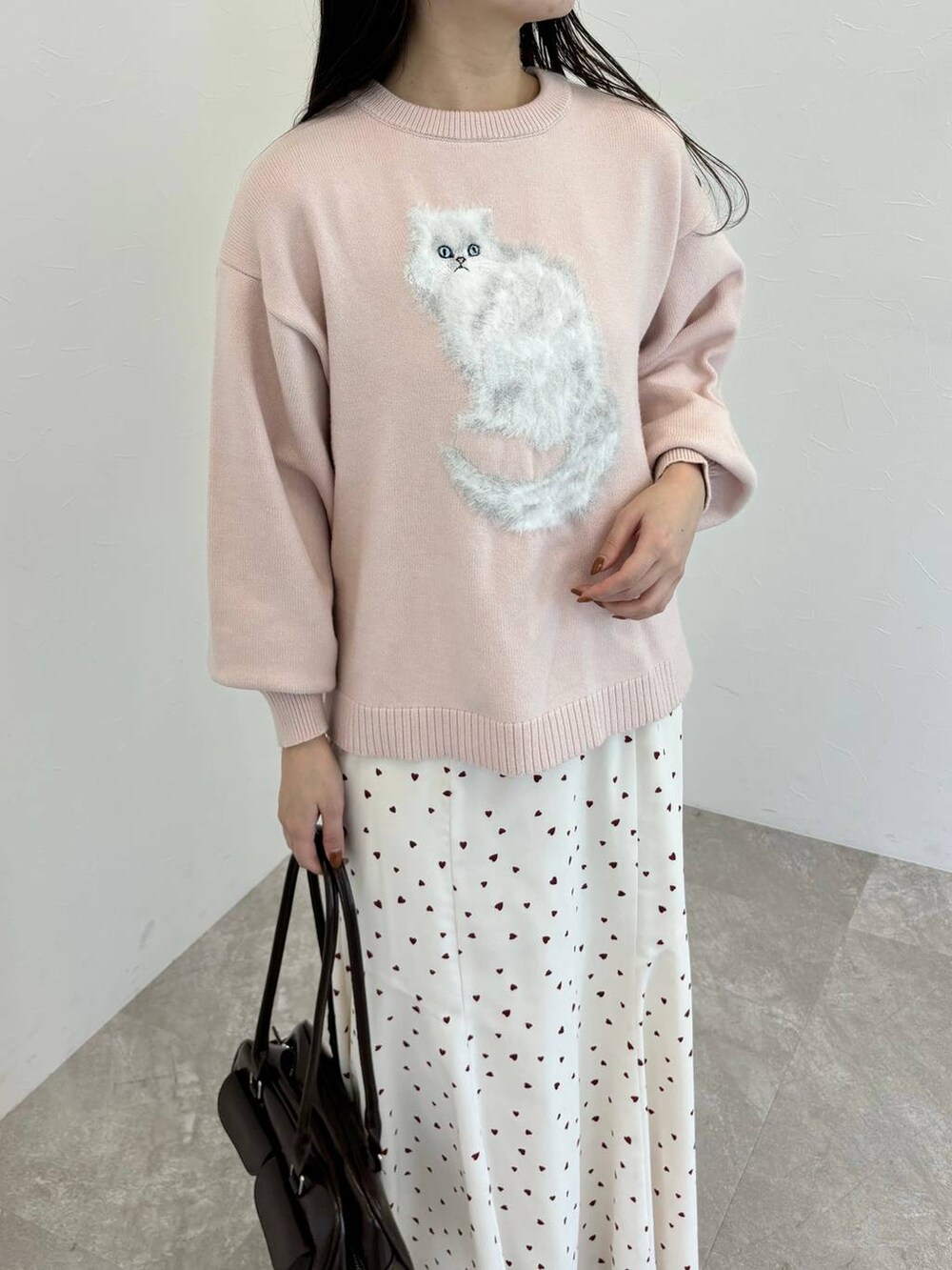 ブラウン系のブーツ、ブラウン系のハンドバッグ、ピンク系のニット/セーターを着用したレディースの秋コーディネートの3枚目の写真