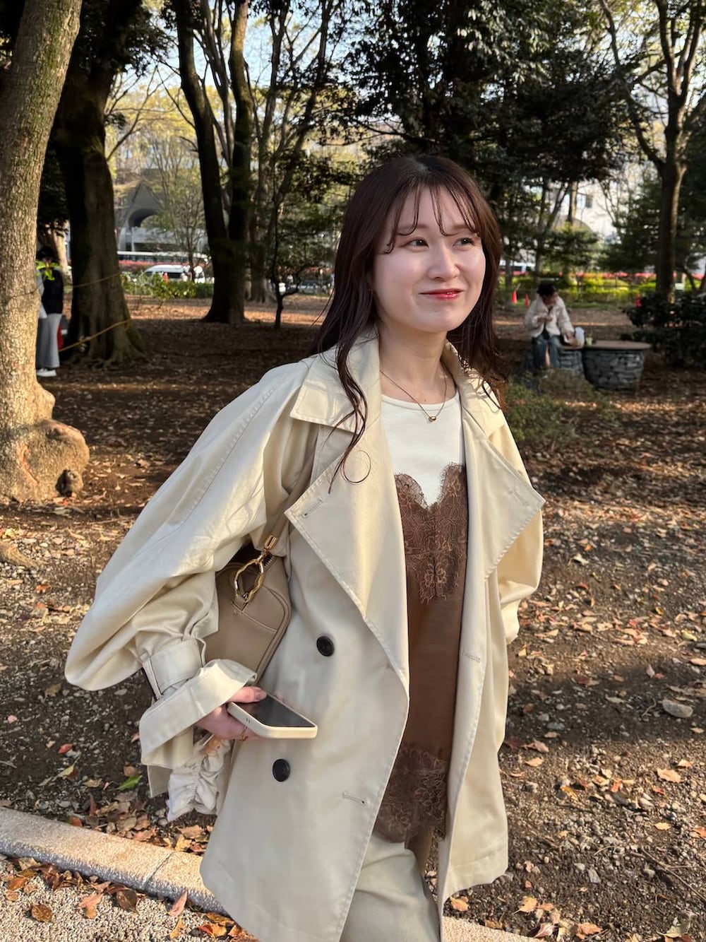 ゴールド系のボストンバッグ、ブラウン系のキャミソール、ホワイト系のスマホグッズを着用したレディースの春コーディネートの3枚目の写真