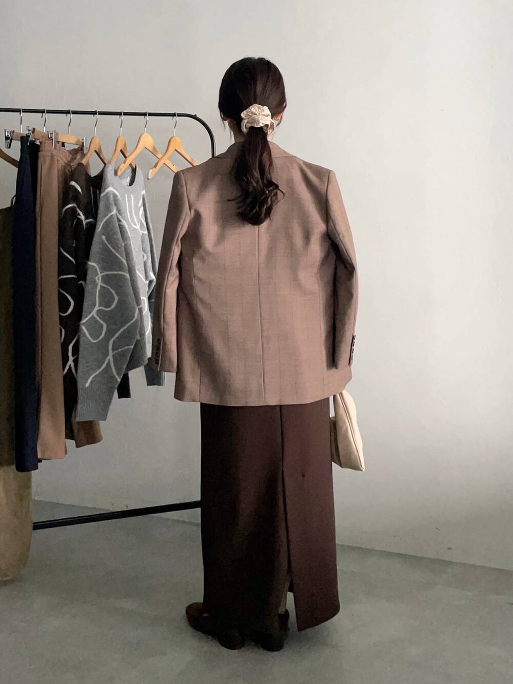 ベージュ系のハンドバッグ、ベージュ系のテーラードジャケット、ブラウン系のスカートを着用したレディースの秋コーディネートの2枚目の写真