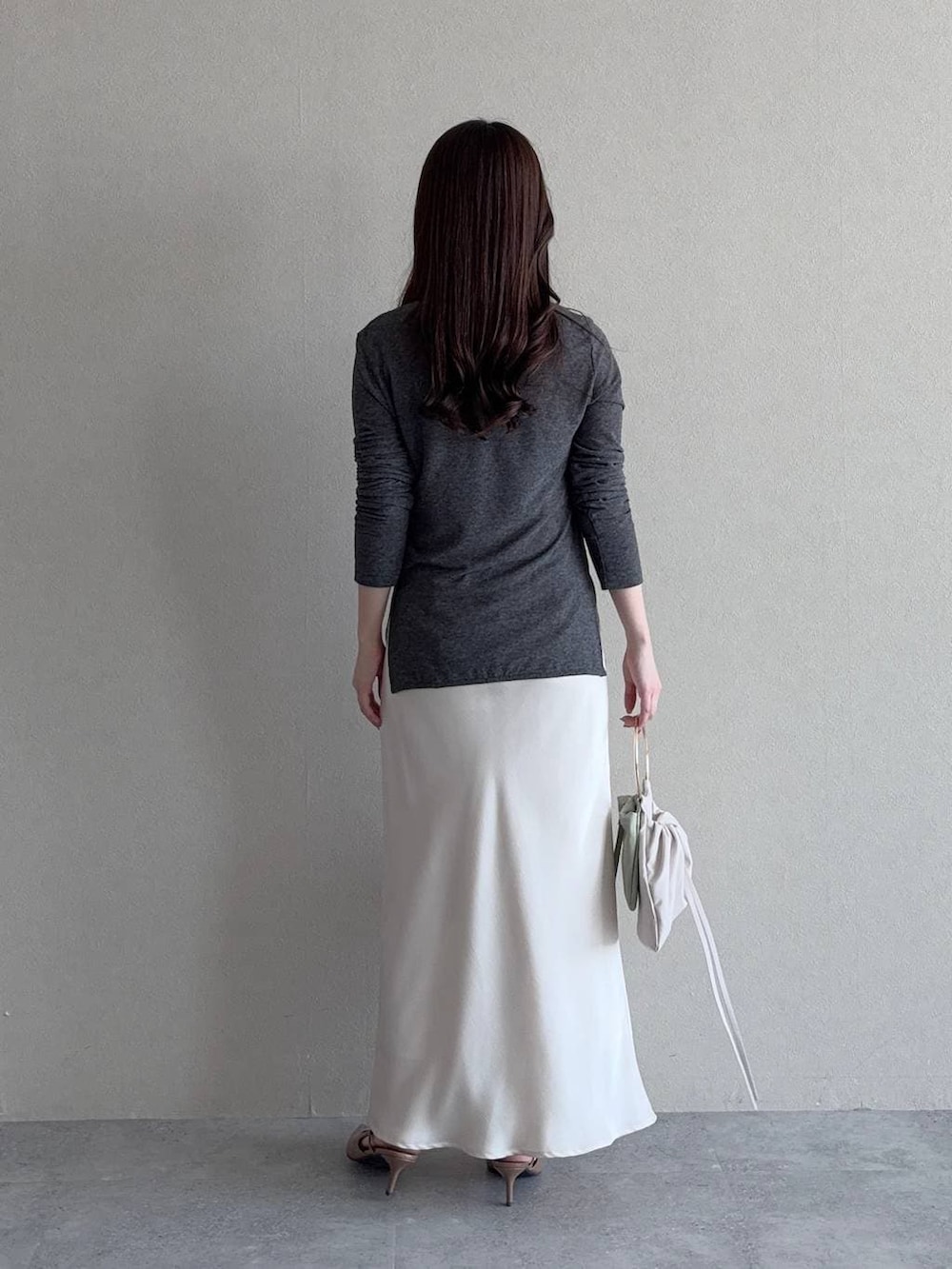 ブラウン系のサンダル、ホワイト系のスカート、グリーン系のハンドバッグを着用したレディースの春コーディネートの2枚目の写真