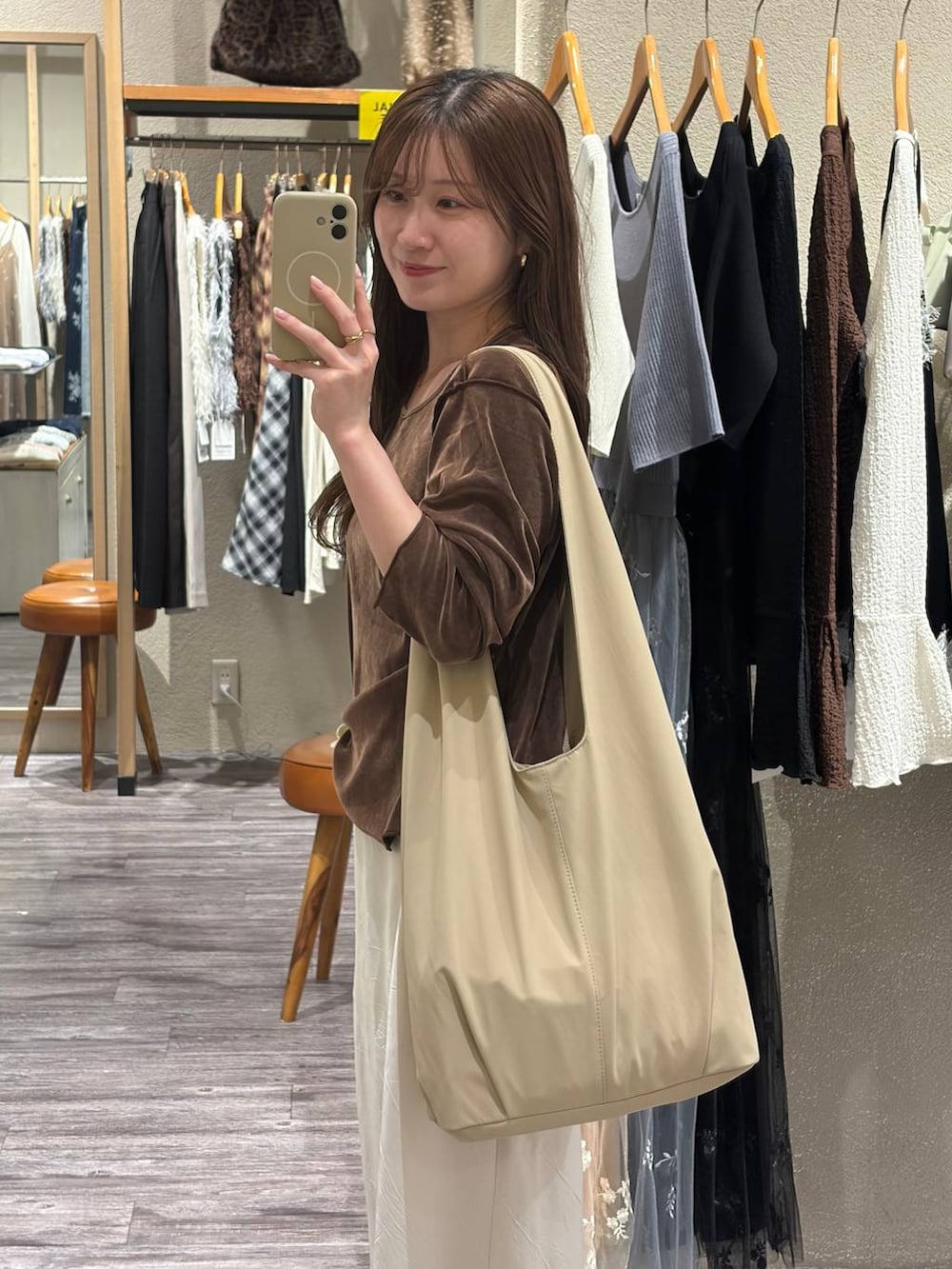 ベージュ系のトートバッグ、ホワイト系のスカート、ブラウン系のTシャツ/カットソーを着用したレディースの秋コーディネートの2枚目の写真
