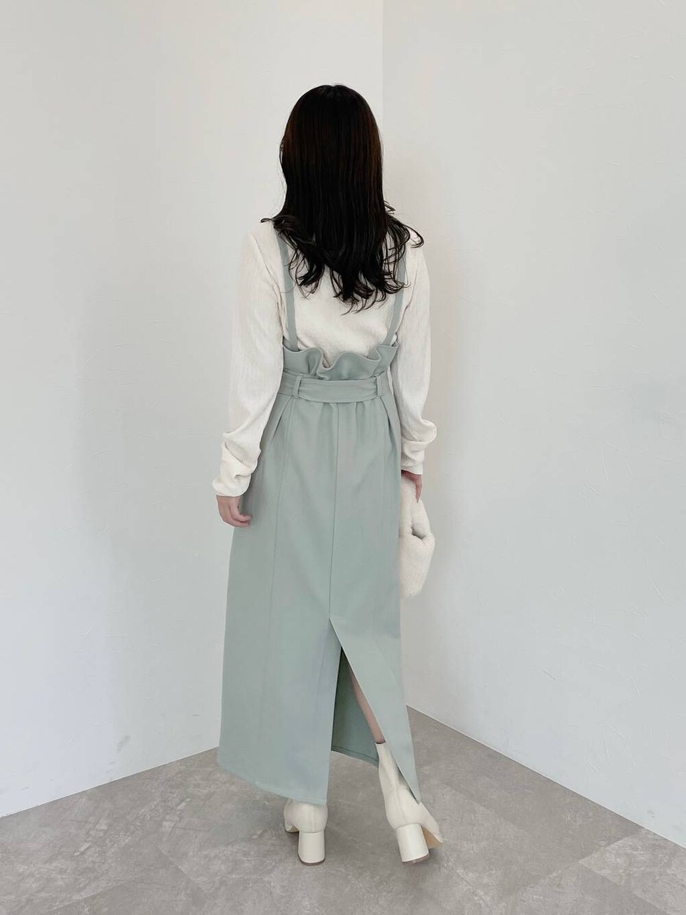 ホワイト系のブーツ、ホワイト系のハンドバッグ、グリーン系のスカートを着用したレディースの冬コーディネートの2枚目の写真