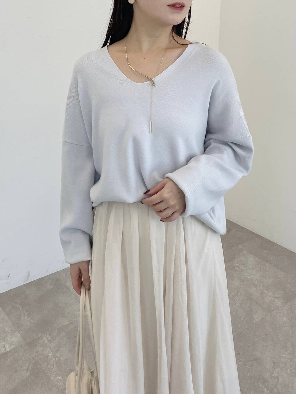 ホワイト系のブーツ、グレー系のニット/セーター、ホワイト系のハンドバッグを着用したレディースの冬コーディネートの3枚目の写真