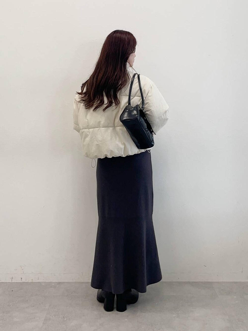 ホワイト系のブルゾン、ブラック系のブーツ、グレー系のワンピースを着用したレディースの秋コーディネートの2枚目の写真