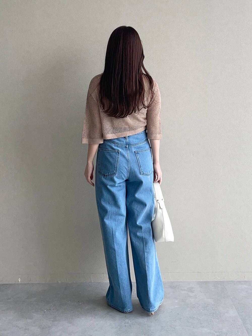 ブルー系のデニムパンツ、ベージュ系のカーディガン/ボレロ、ホワイト系のショルダーバッグを着用したレディースの春コーディネートの2枚目の写真