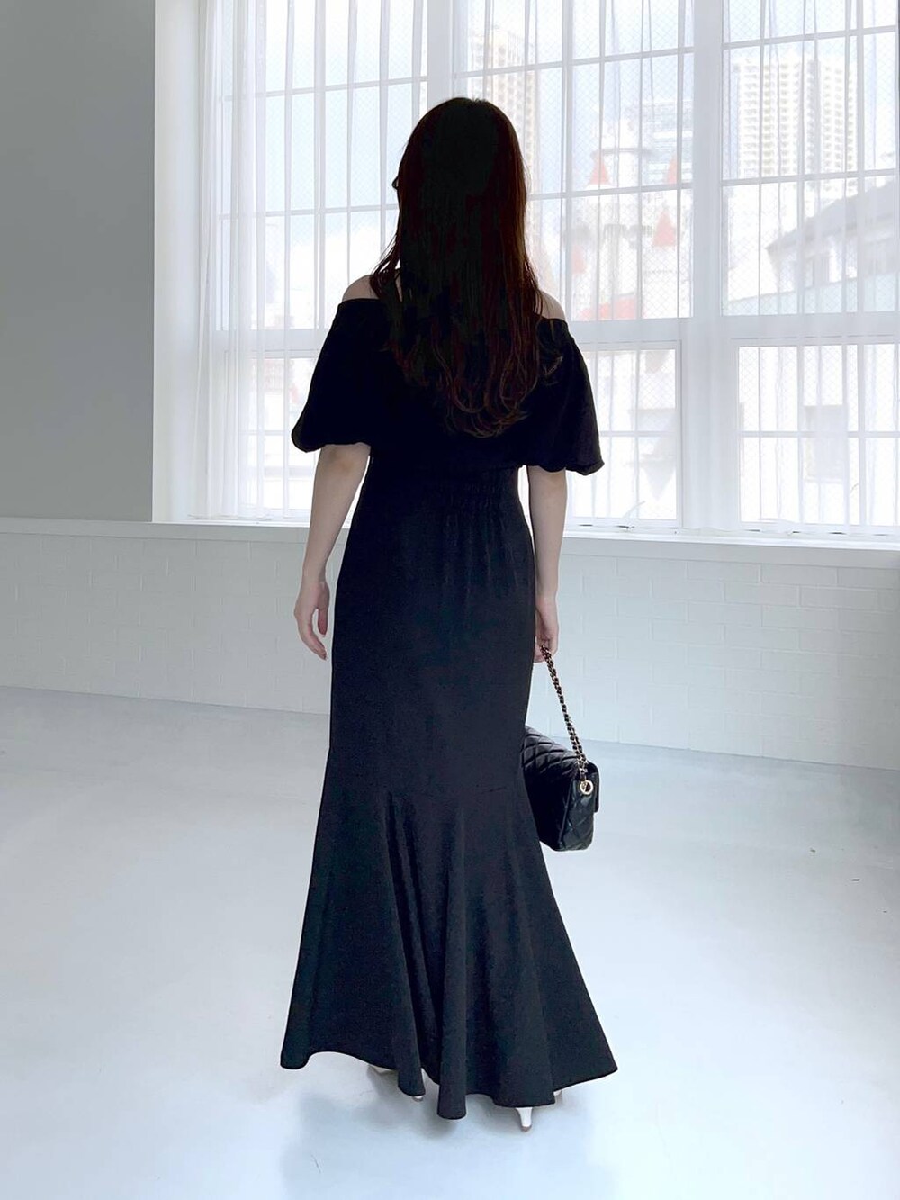 ブラック系のニット/セーター、ブラック系のショルダーバッグ、ホワイト系のサンダルを着用したレディースの夏コーディネートの2枚目の写真