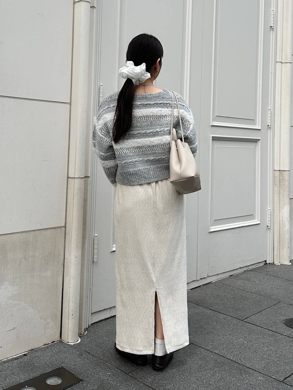 ホワイト系のスカート、グレー系のニット/セーターを着用したレディースの冬コーディネートの2枚目の写真