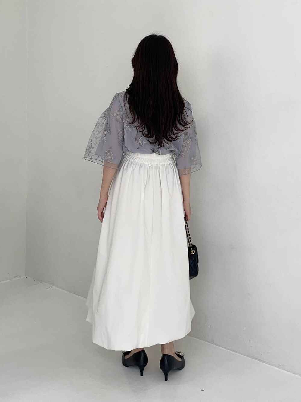 ブラック系のパンプス、ブルー系のシャツ/ブラウス、ブラック系のショルダーバッグを着用したレディースの夏コーディネートの2枚目の写真