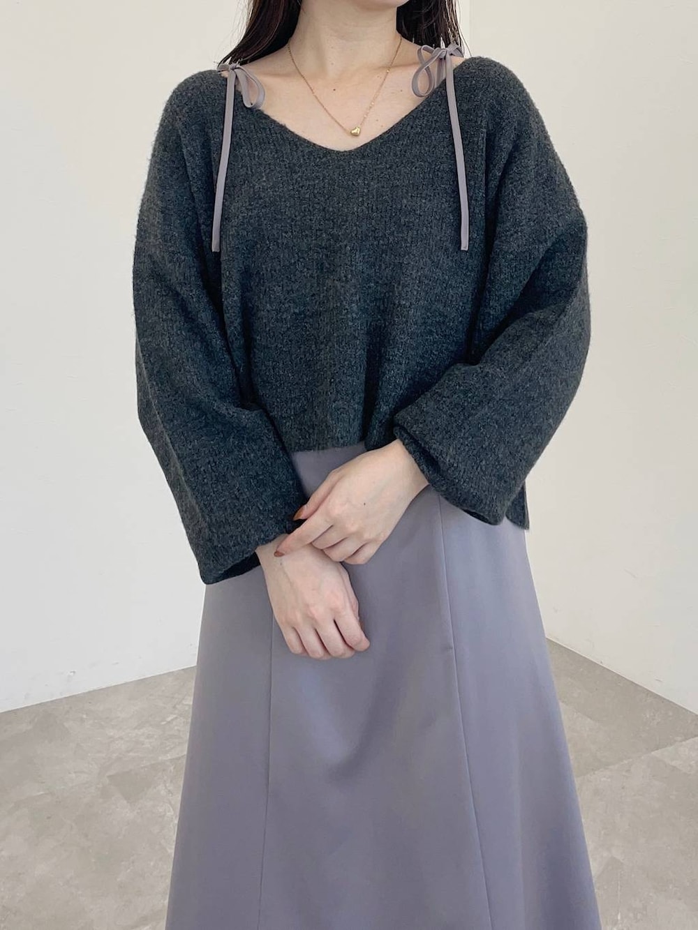 ブラック系のショルダーバッグ、ブラウン系のブーツ、グレー系のワンピースを着用したレディースの冬コーディネートの3枚目の写真