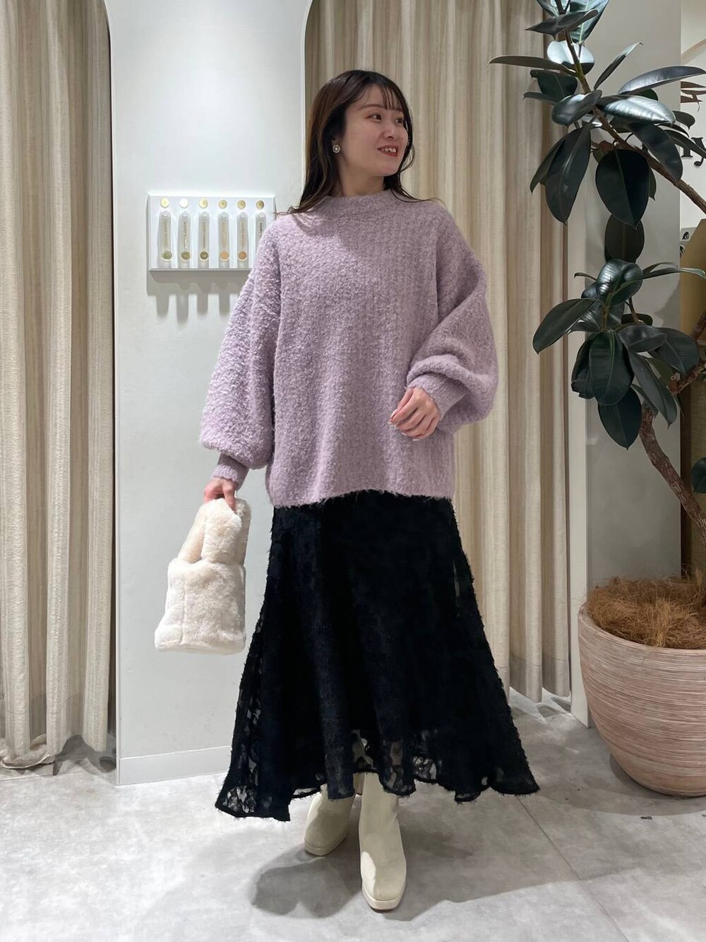 ホワイト系のブーツ、ピンク系のニット/セーター、ホワイト系のハンドバッグを着用したレディースの冬コーディネートの2枚目の写真