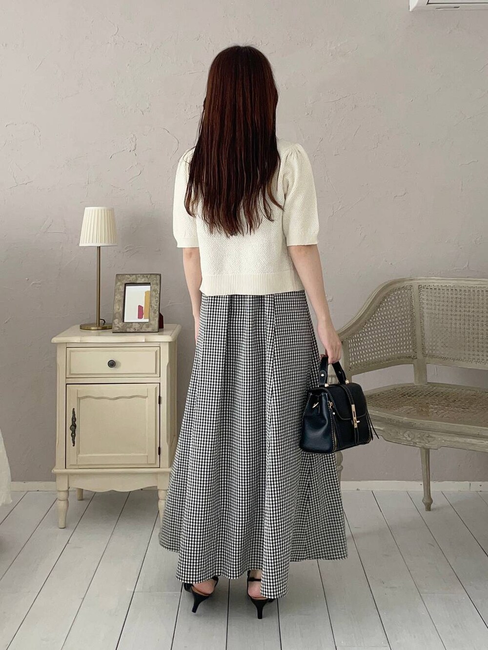 ブラック系のパンプス、ブラック系のショルダーバッグ、ホワイト系のカーディガン/ボレロを着用したレディースの夏コーディネートの2枚目の写真