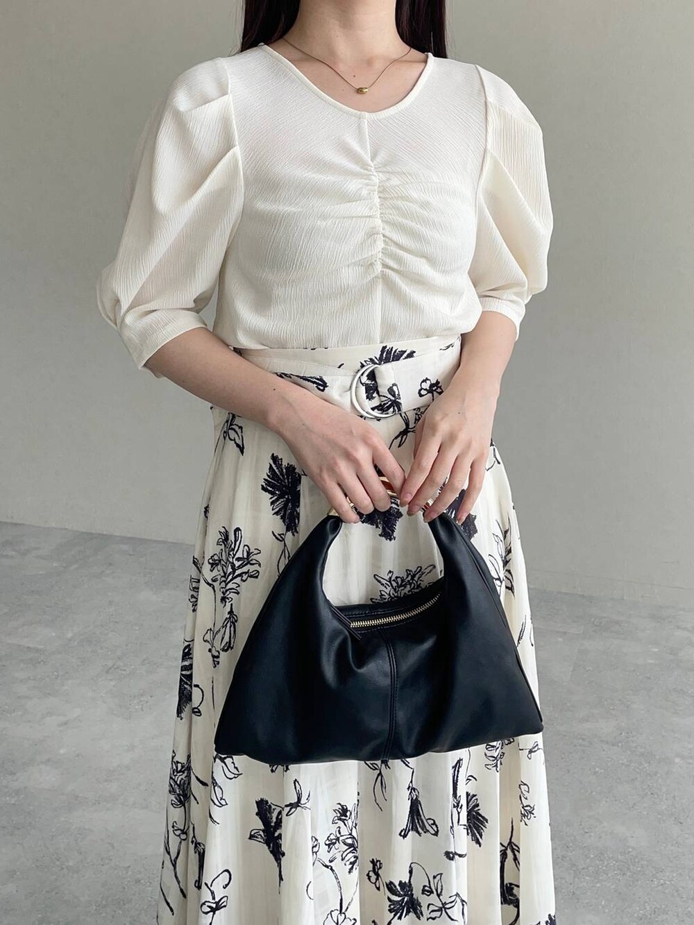 ブラック系のハンドバッグ、ホワイト系のTシャツ/カットソー、ホワイト系のスカートを着用したレディースの秋コーディネートの3枚目の写真