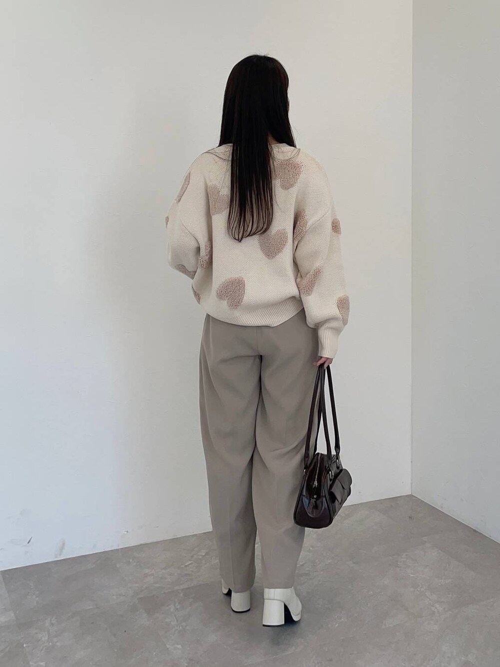 ホワイト系のブーツ、ベージュ系のその他パンツ、ブラウン系のハンドバッグを着用したレディースの冬コーディネートの2枚目の写真