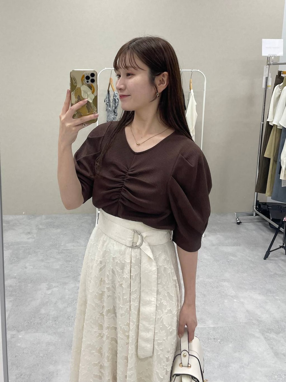 ホワイト系のショルダーバッグ、ブラウン系のTシャツ/カットソー、ホワイト系のスカートを着用したレディースの秋コーディネートの2枚目の写真