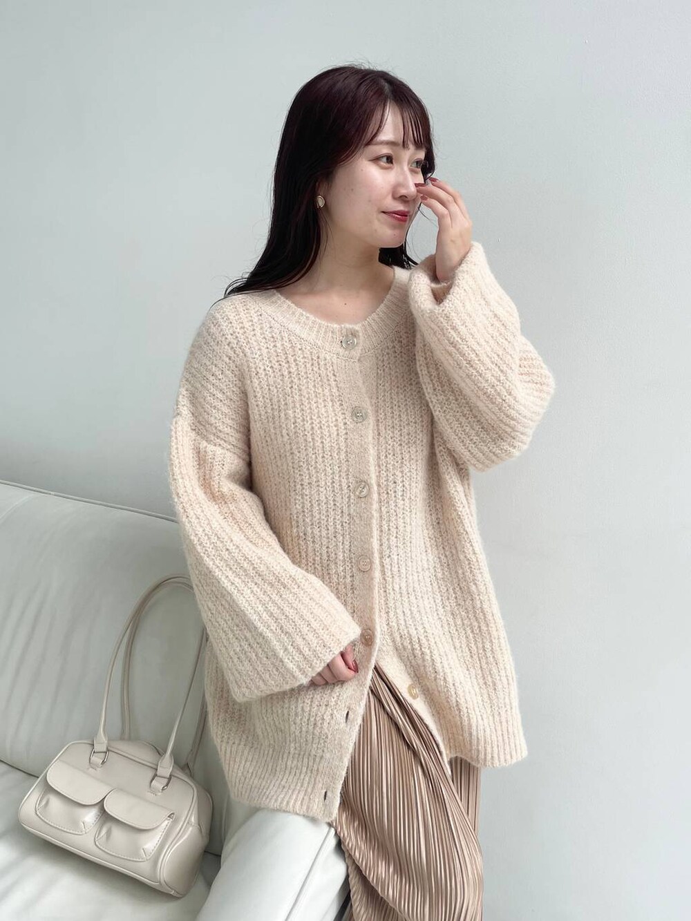 ベージュ系のスカート、ブラウン系のブーツ、ホワイト系のハンドバッグを着用したレディースの冬コーディネートの3枚目の写真