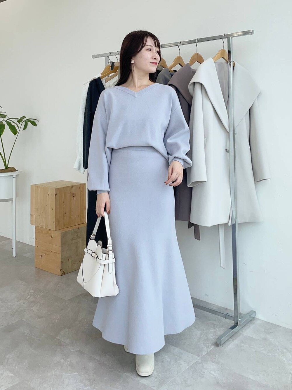 ホワイト系のノーカラーコート、ホワイト系のショルダーバッグ、ホワイト系のブーツを着用したレディースの秋コーディネートの3枚目の写真