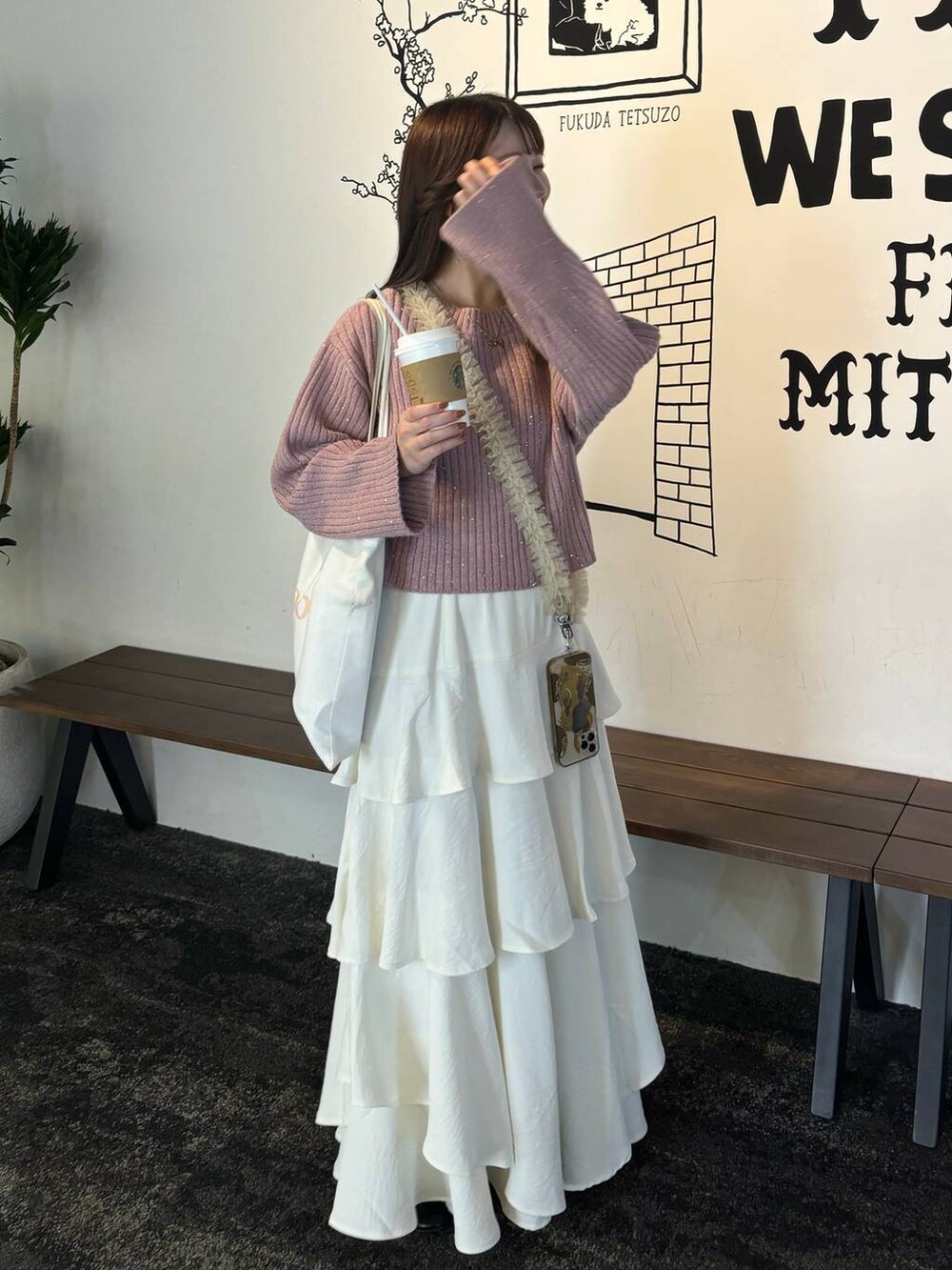 ホワイト系のスカート、ピンク系のニット/セーター、ベージュ系のスマホグッズを着用したレディースの秋コーディネートの2枚目の写真