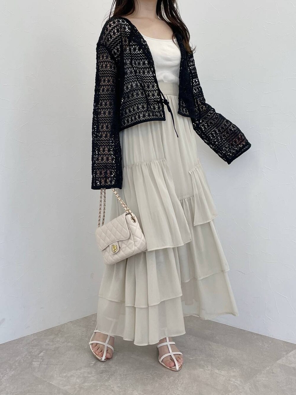 ホワイト系のスカート、ブラック系のカーディガン/ボレロ、ホワイト系のショルダーバッグを着用したレディースの春コーディネートの4枚目の写真