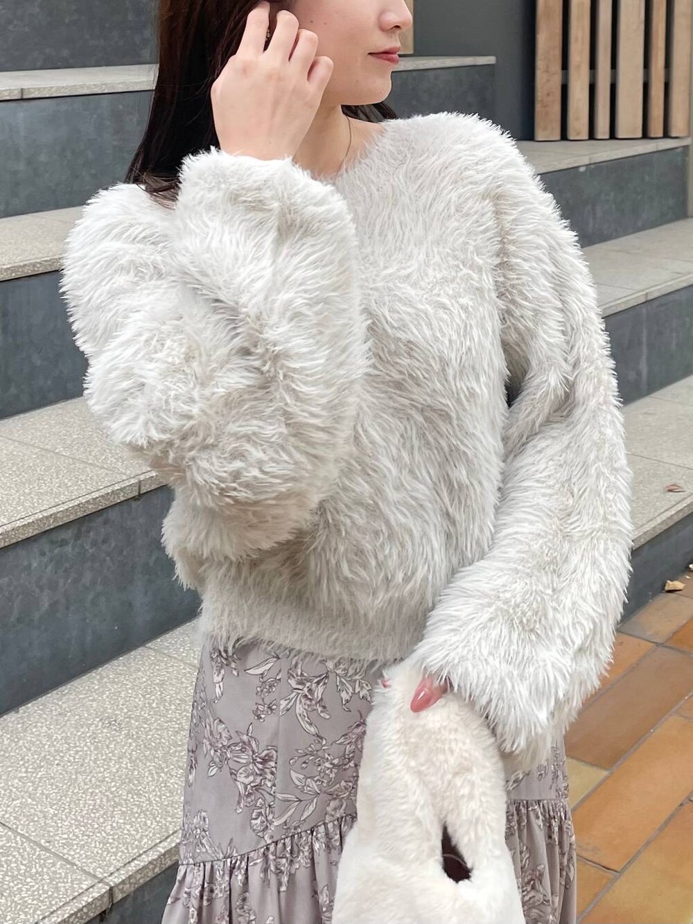 ホワイト系のハンドバッグ、ベージュ系のスカート、ベージュ系のニット/セーターを着用したレディースの冬コーディネートの3枚目の写真