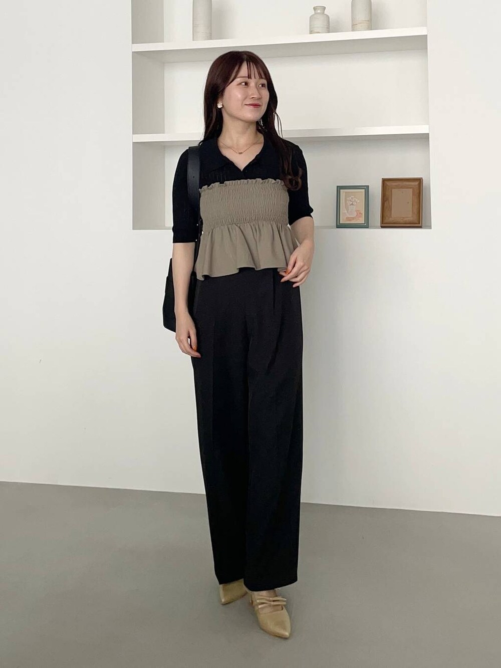 ブラック系のスラックス、ゴールド系のパンプス、グリーン系のスカートを着用したレディースの夏コーディネートの2枚目の写真