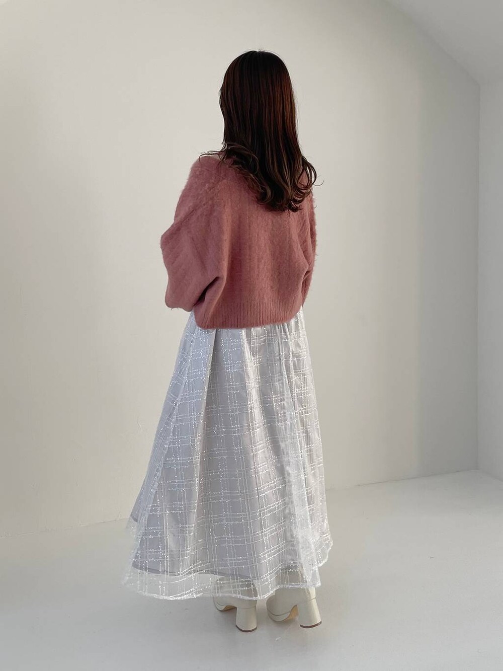 ホワイト系のハンドバッグ、ホワイト系のブーツ、ピンク系のカーディガン/ボレロを着用したレディースの秋コーディネートの2枚目の写真