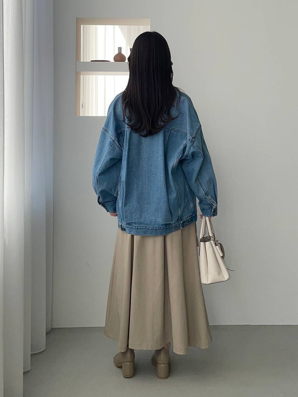 ブルー系のデニムジャケット、ホワイト系のショルダーバッグ、ブラウン系のパンプスを着用したレディースの冬コーディネートの2枚目の写真