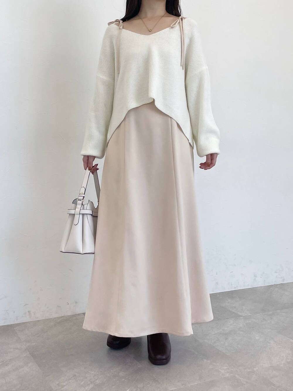 ホワイト系のショルダーバッグ、ブラウン系のブーツ、ベージュ系のワンピースを着用したレディースの冬コーディネートの4枚目の写真