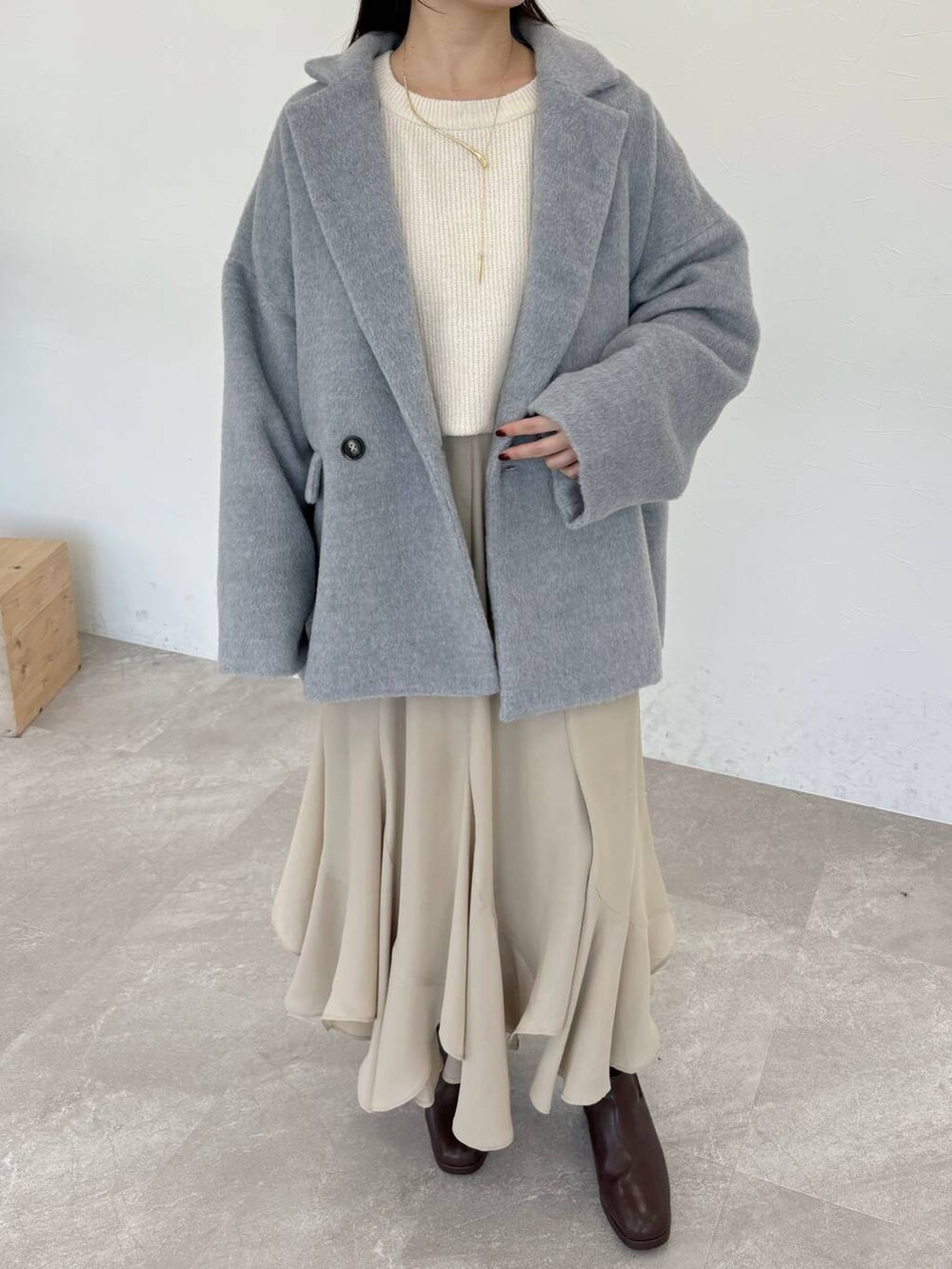 ホワイト系のショルダーバッグ、ブラウン系のブーツ、ホワイト系のニット/セーターを着用したレディースの冬コーディネートの3枚目の写真