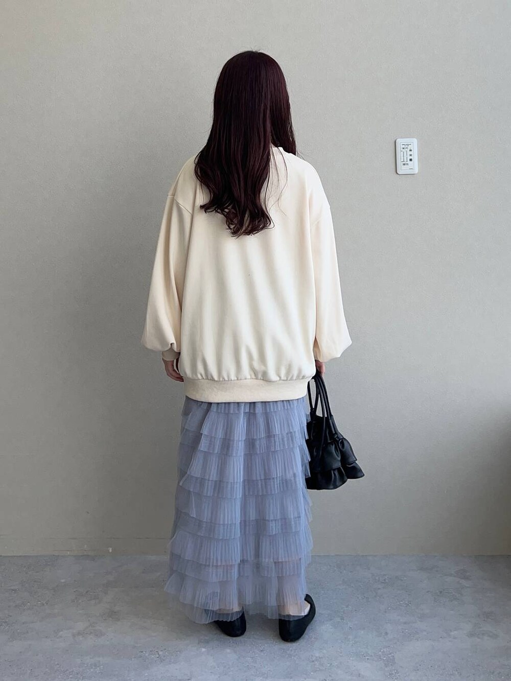 ブラック系のショルダーバッグ、ホワイト系のスウェット、グレー系のスカートを着用したレディースの冬コーディネートの2枚目の写真