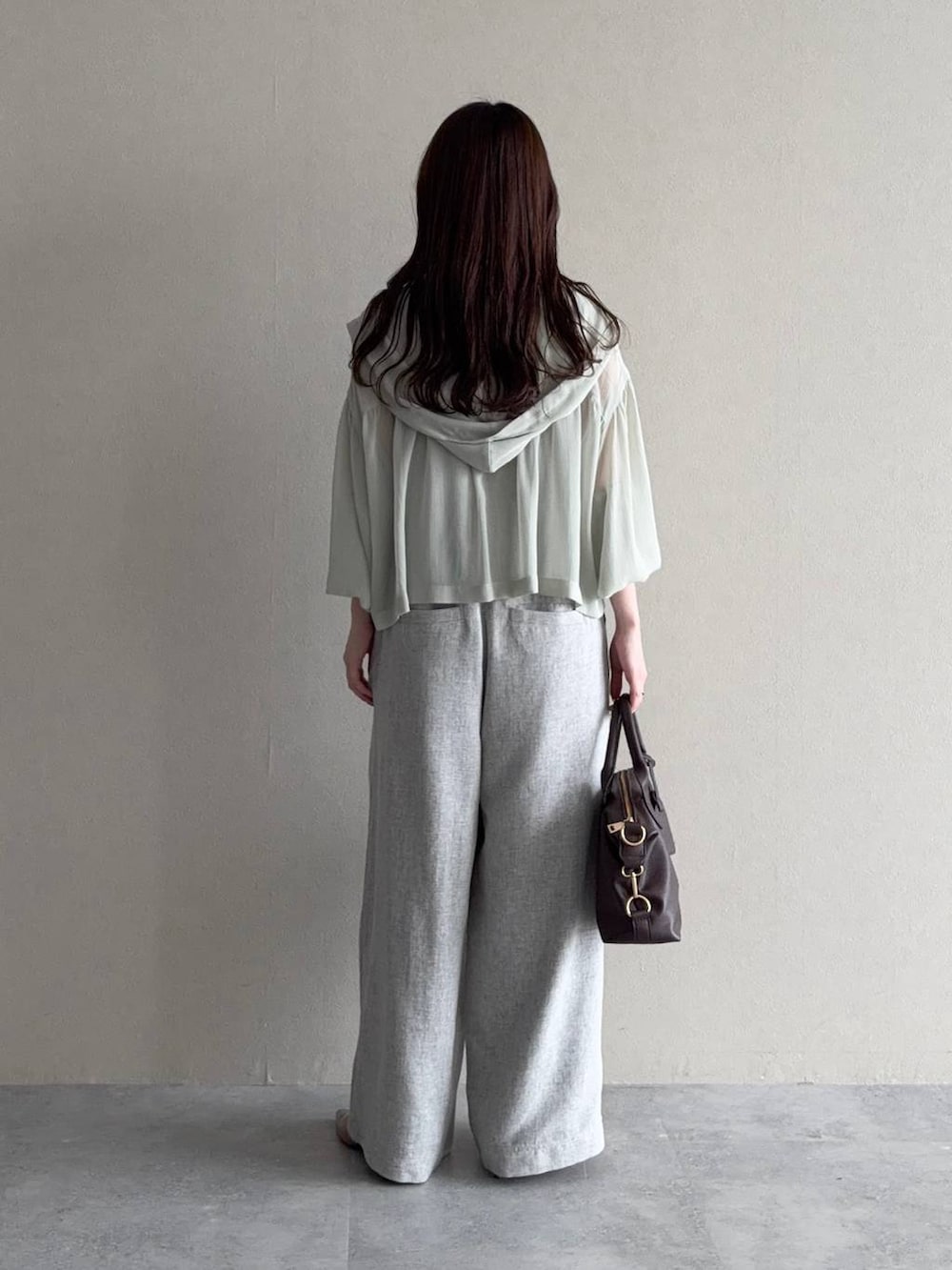 グリーン系のパーカー、ブラウン系のボストンバッグ、ブラウン系のサンダルを着用したレディースの春コーディネートの2枚目の写真