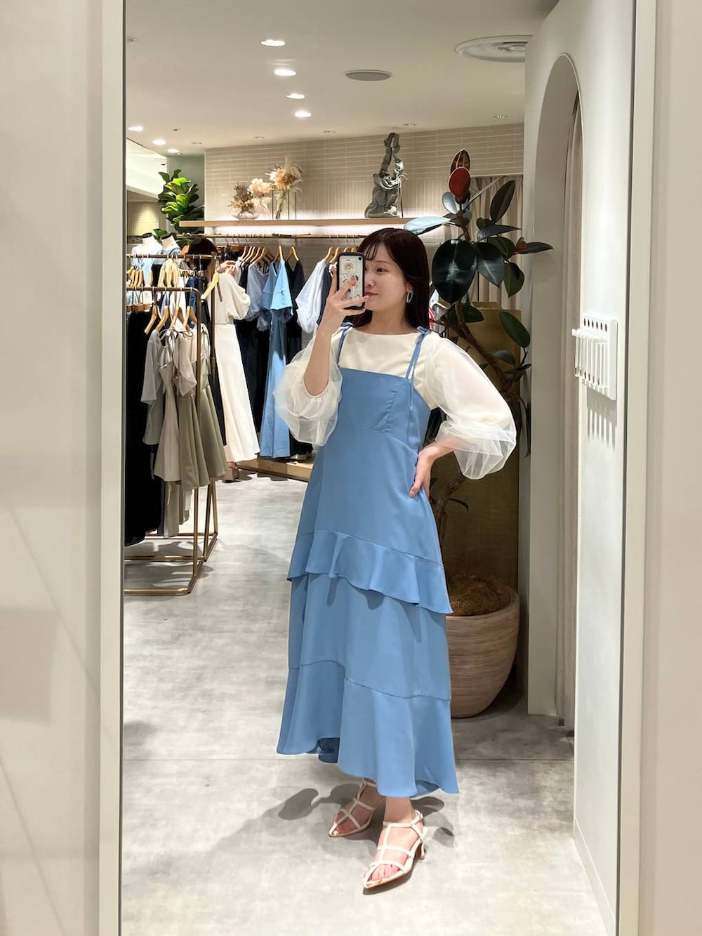 シルバー系のハンドバッグ、ホワイト系のサンダル、ブルー系のワンピースを着用したレディースの春コーディネートの4枚目の写真