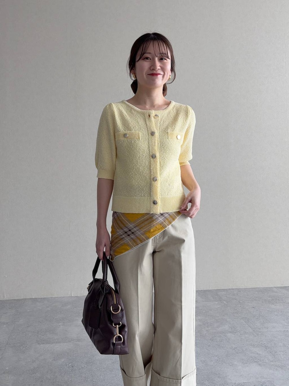 ブラウン系のボストンバッグ、イエロー系のカーディガン/ボレロ、ブラウン系のサンダルを着用したレディースの春コーディネートの3枚目の写真
