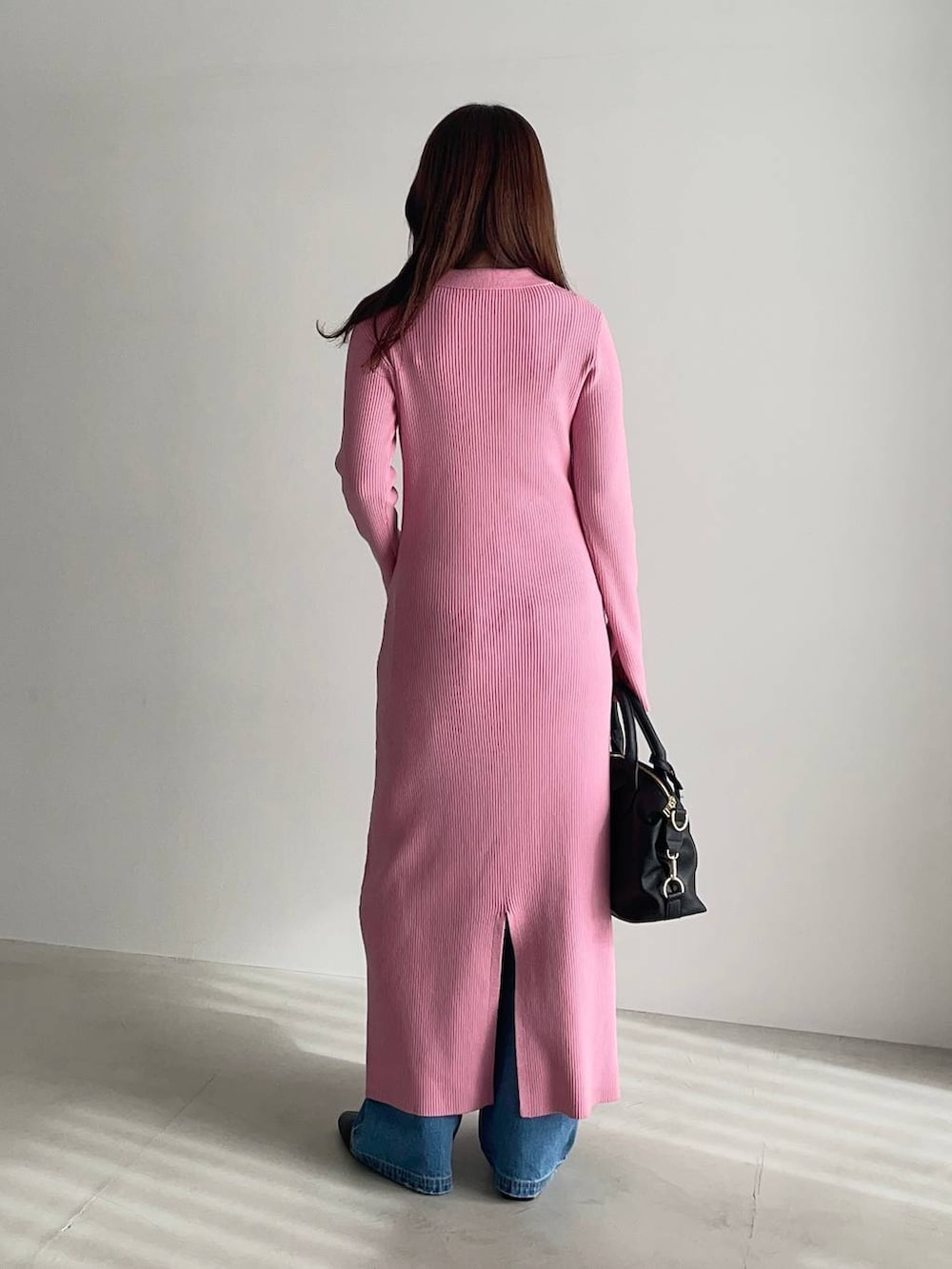 ブラック系のボストンバッグ、ブラック系のブーツ、ピンク系のワンピースを着用したレディースの冬コーディネートの2枚目の写真