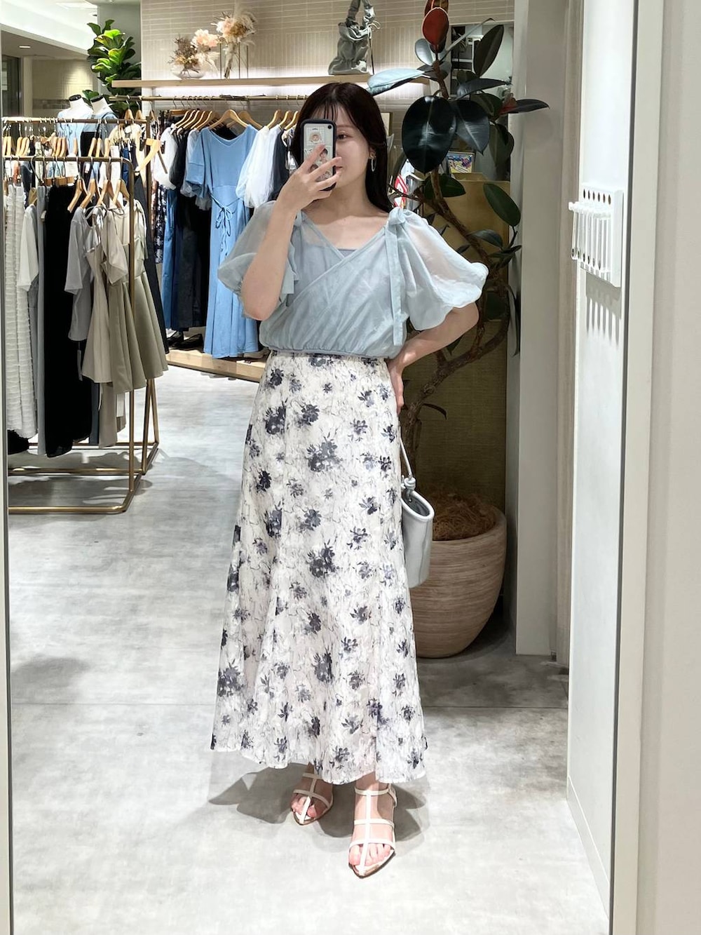 シルバー系のハンドバッグ、ホワイト系のサンダル、ホワイト系のスカートを着用したレディースの春コーディネートの4枚目の写真