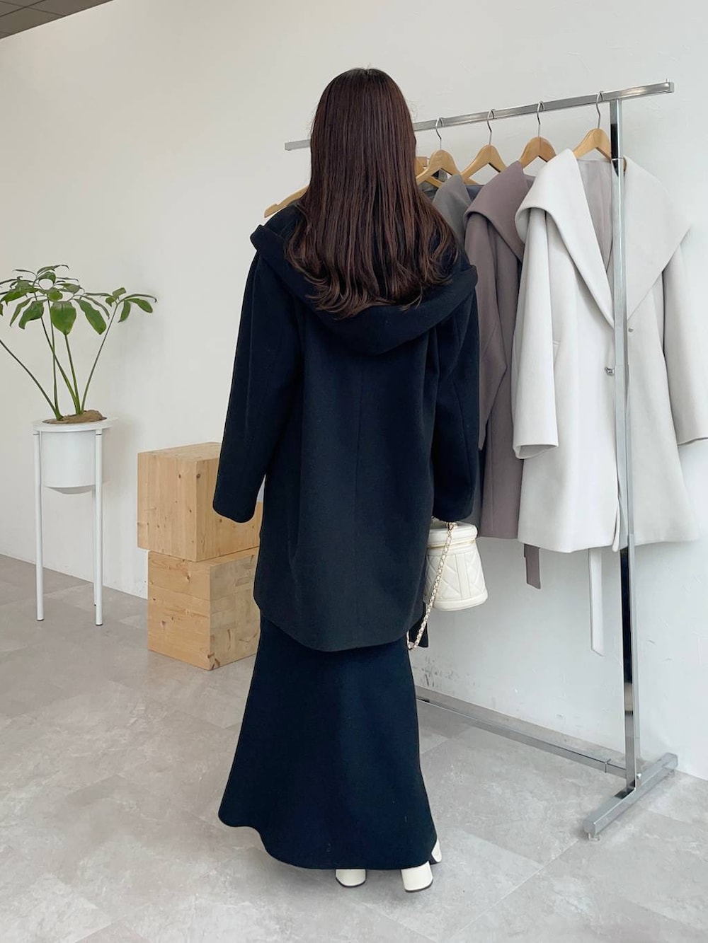 ブラック系のその他アウター、ホワイト系のブーツ、ホワイト系のショルダーバッグを着用したレディースの秋コーディネートの2枚目の写真