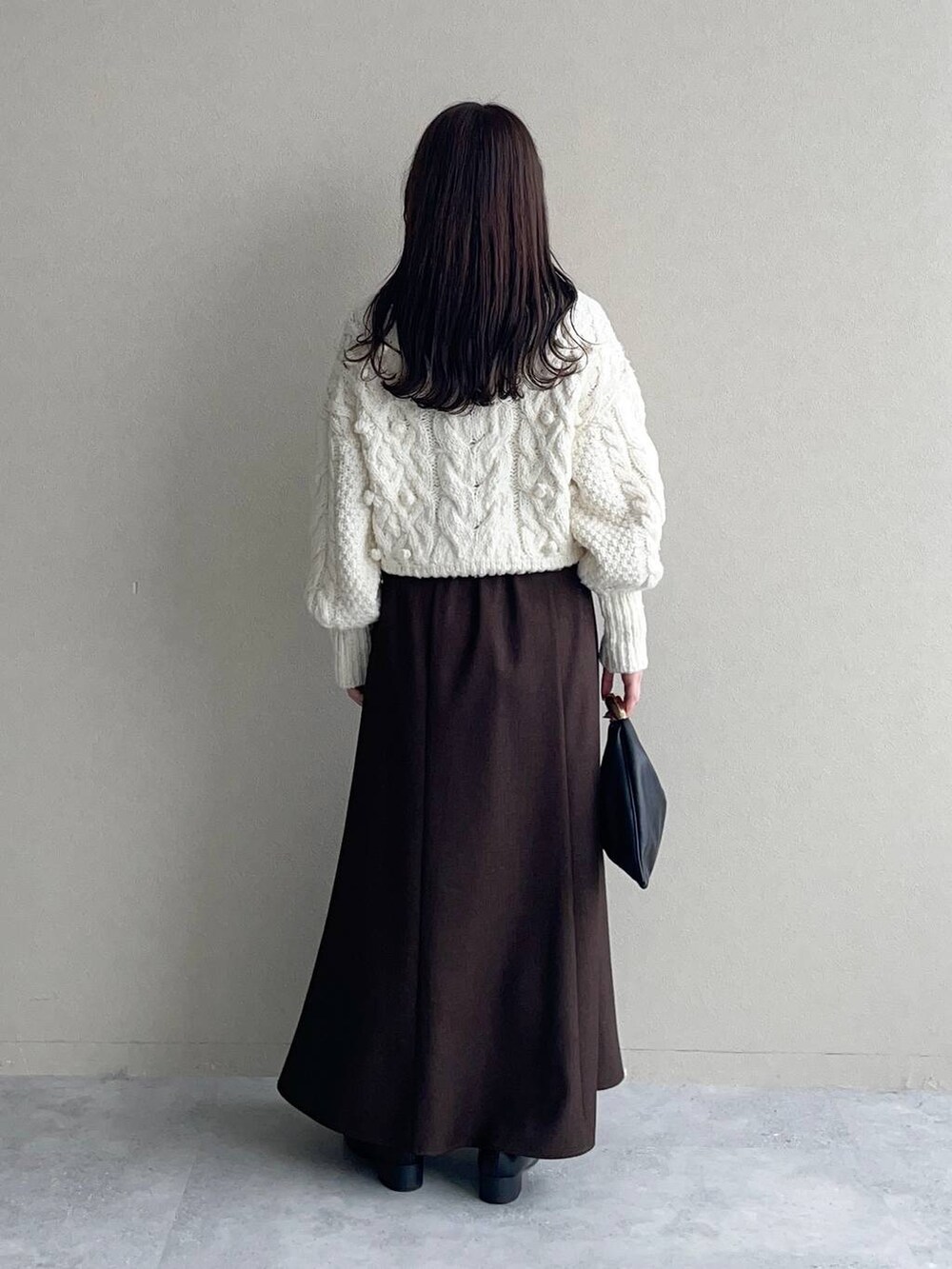 ベージュ系のチェスターコート、ブラック系のハンドバッグ、ブラウン系のスカートを着用したレディースの秋コーディネートの4枚目の写真