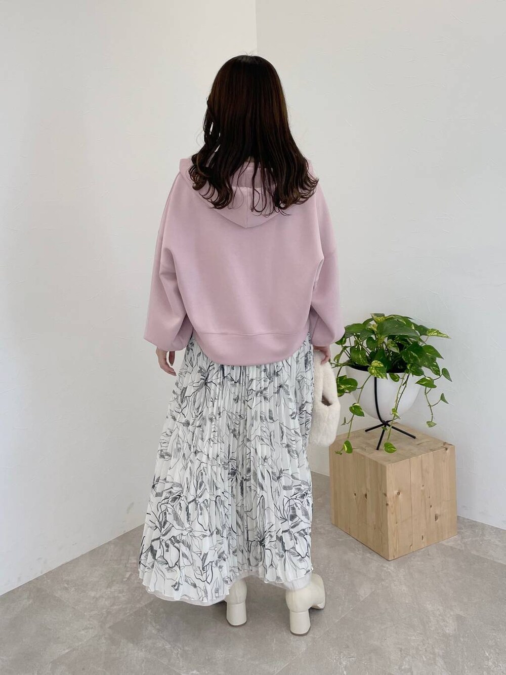 ピンク系のパーカー、ホワイト系のブーツ、ホワイト系のハンドバッグを着用したレディースの冬コーディネートの2枚目の写真