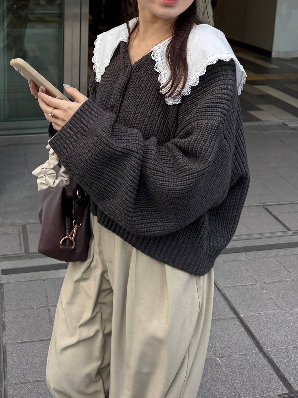 ブラウン系のボストンバッグ、グレー系のカーディガン/ボレロを着用したレディースの冬コーディネートの2枚目の写真