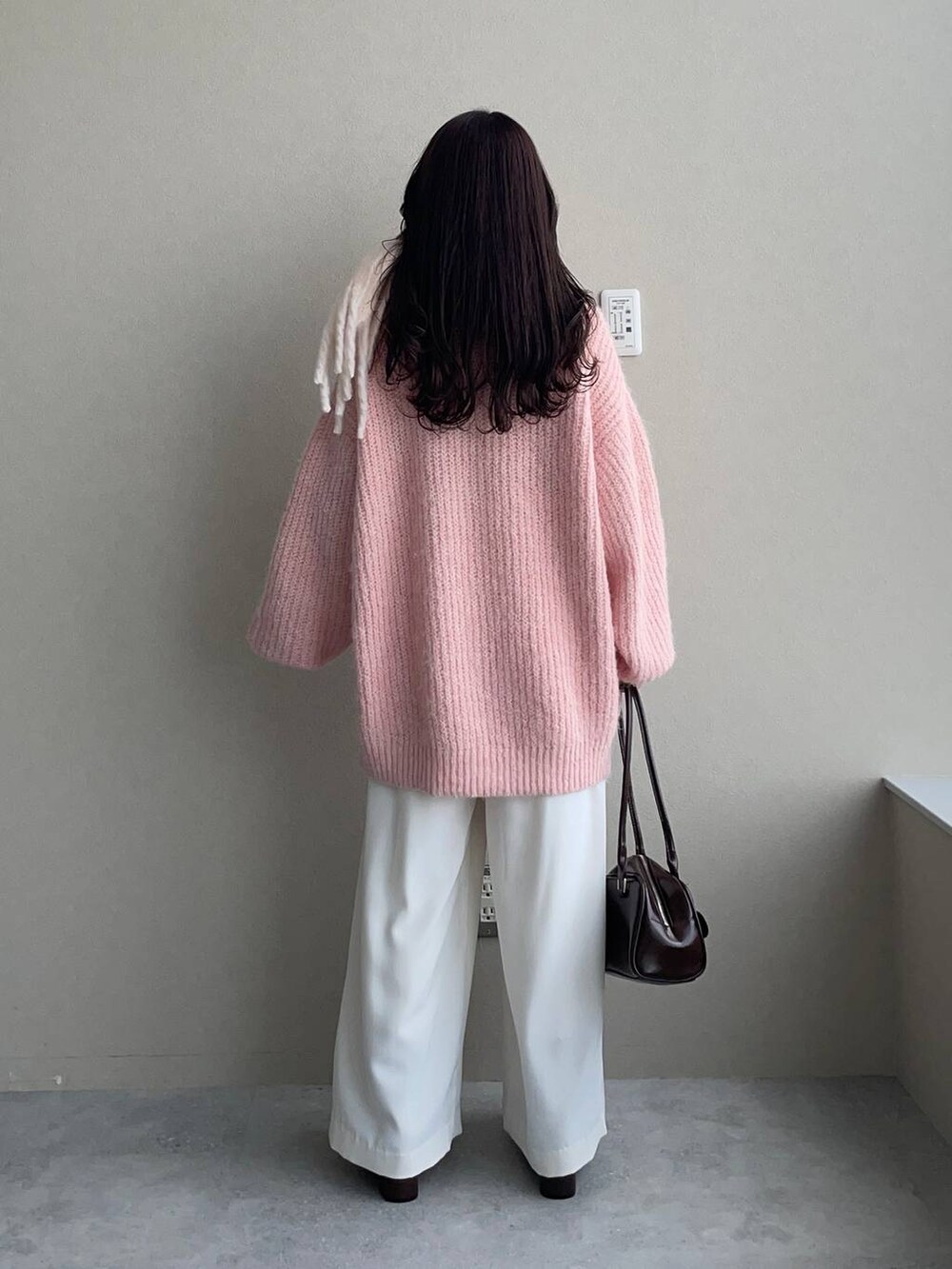 ブラウン系のブーツ、ピンク系のカーディガン/ボレロ、ブラウン系のハンドバッグを着用したレディースの秋コーディネートの2枚目の写真