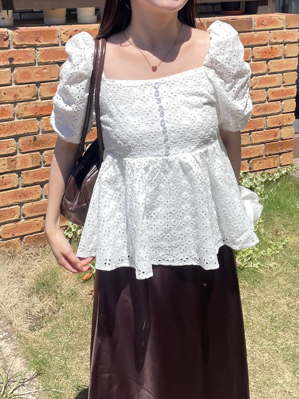 ブラウン系のスカート、ホワイト系のシャツ/ブラウスを着用したレディースの夏コーディネートの3枚目の写真