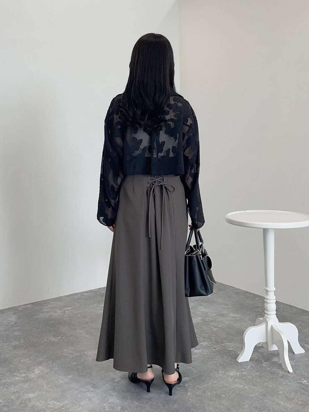 ブラック系のショルダーバッグ、ブラック系のワンピース、ブラック系のパンプスを着用したレディースの秋コーディネートの2枚目の写真