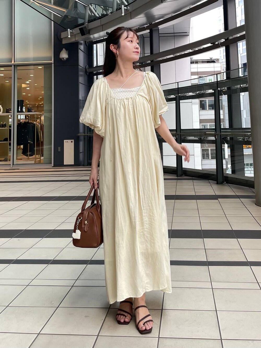 ブラウン系のサンダル、ブラウン系のショルダーバッグ、ホワイト系のワンピースを着用したレディースの夏コーディネートの3枚目の写真