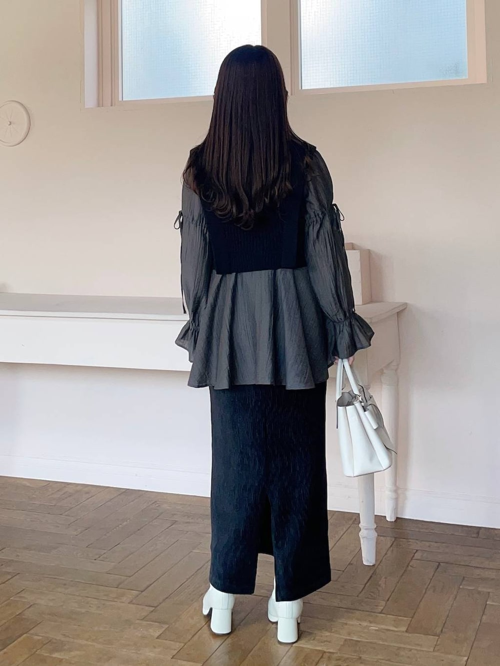 ホワイト系のブーツ、ブラック系のスカート、ブラック系のシャツ/ブラウスを着用したレディースの冬コーディネートの2枚目の写真