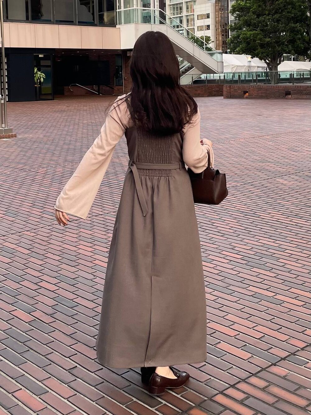 ベージュ系のワンピースを着用したレディースの秋コーディネートの2枚目の写真