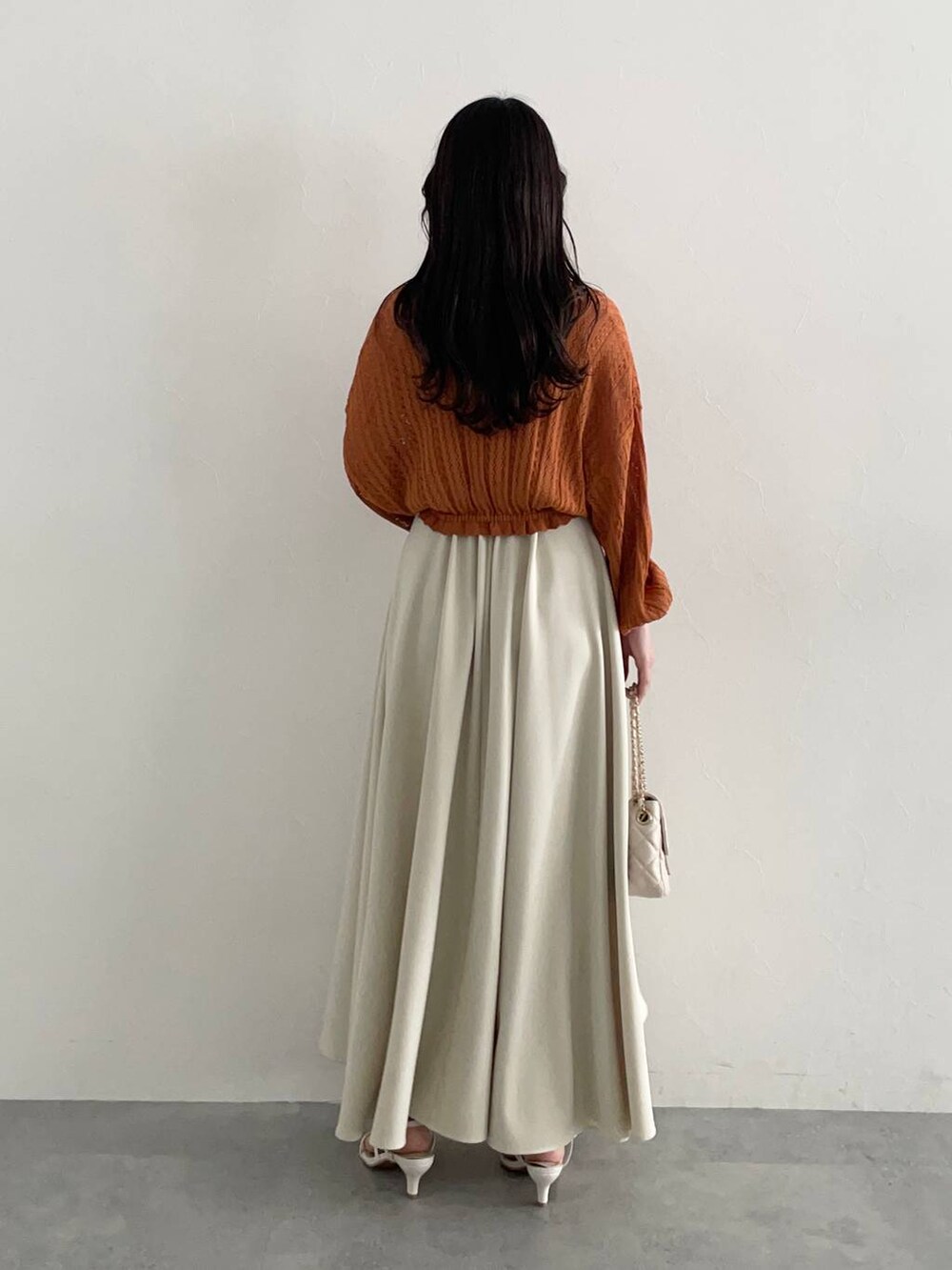 ホワイト系のショルダーバッグ、オレンジ系のカーディガン/ボレロ、ホワイト系のスカートを着用したレディースの夏コーディネートの2枚目の写真