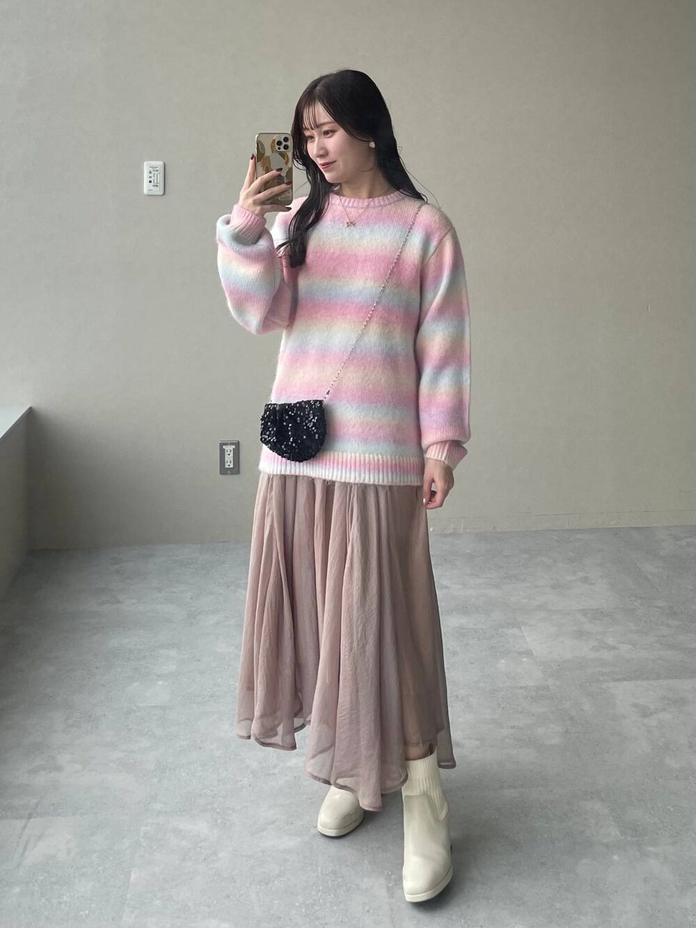 ホワイト系のブーツ、ベージュ系のスカート、ブラック系のショルダーバッグを着用したレディースの秋コーディネートの4枚目の写真