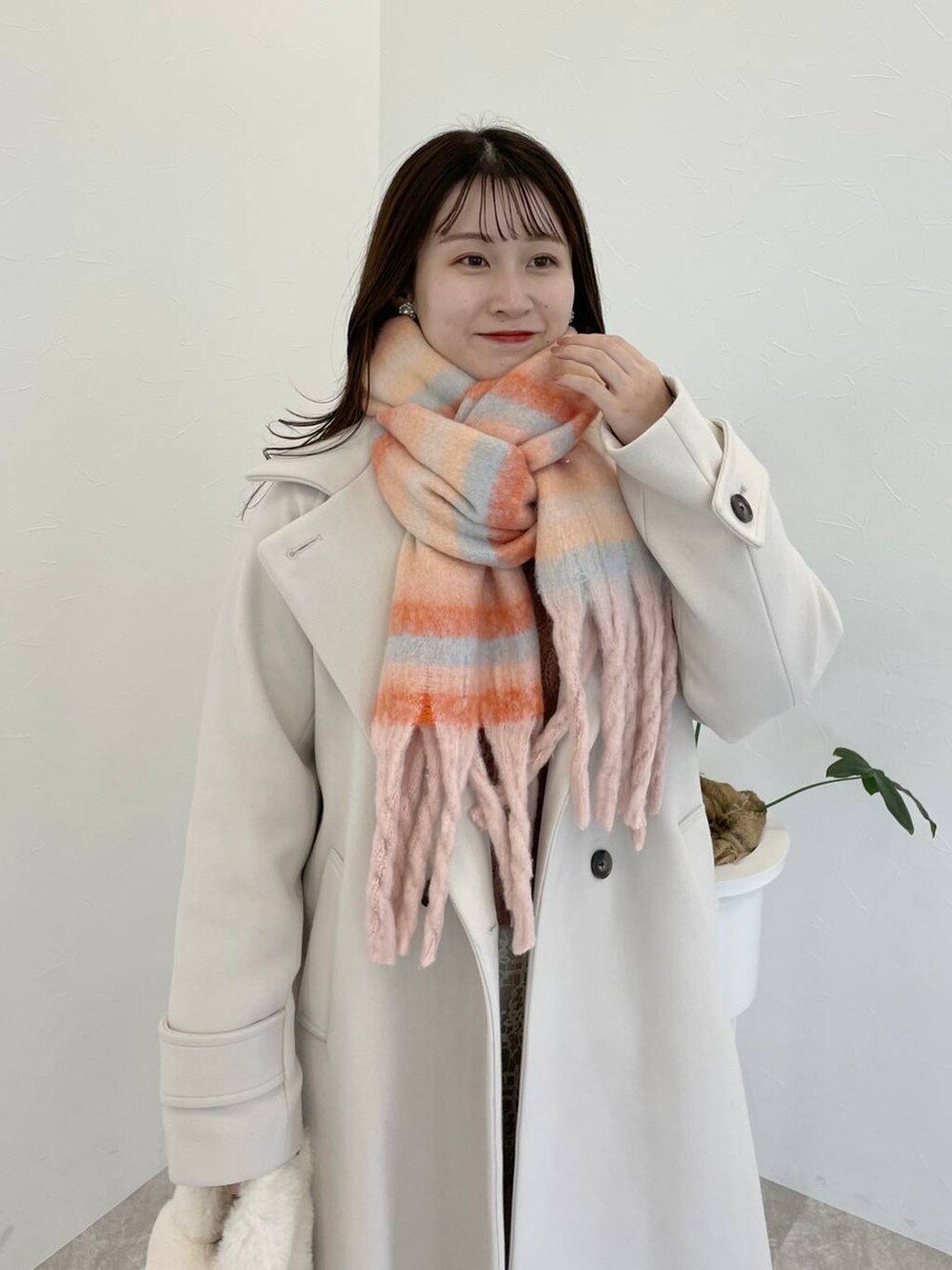 ホワイト系のチェスターコート、グレー系のブーツ、ホワイト系のスカートを着用したレディースの秋コーディネートの3枚目の写真